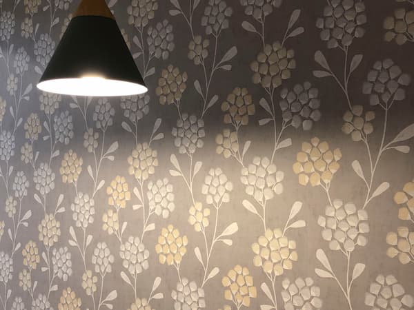 Detalle de empapelado en pared de la cocina con papel pintado y lampara que ilumina la mesa de la cocina